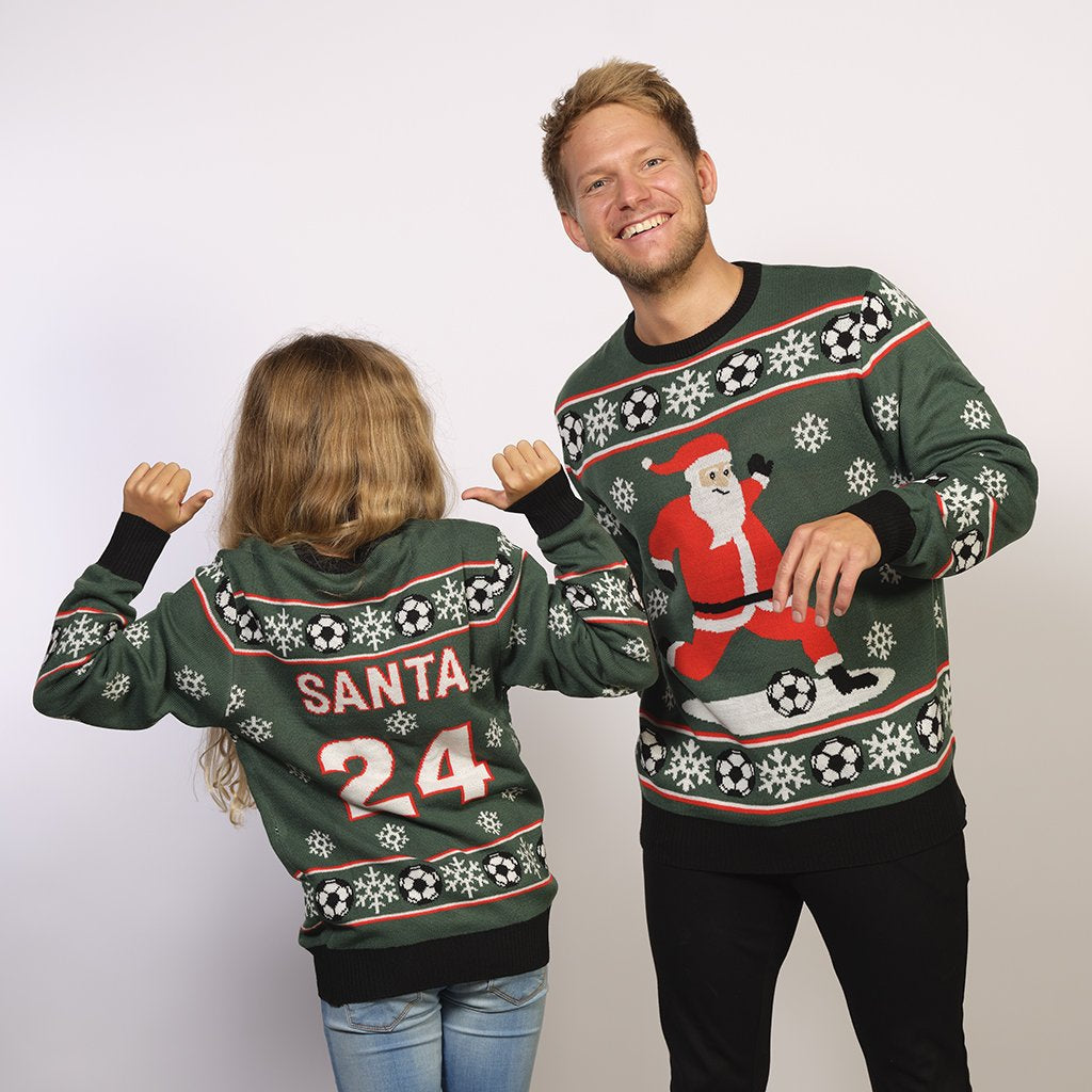 En man och ett barn poserar tillsammans iklädda en grön jultröja med en jultomte som spelar fotboll.